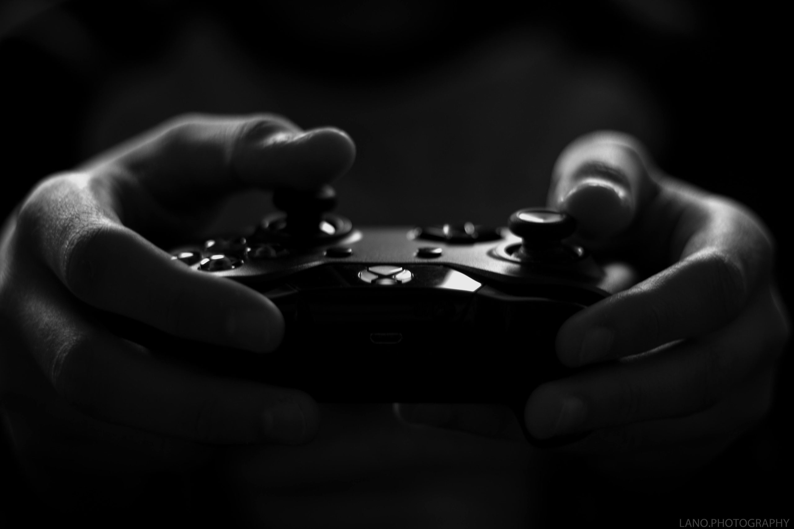 Close-up of hands holding a game controller in a monochrome setting, capturing the essence of gaming.